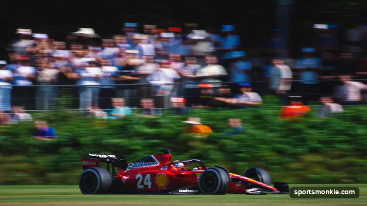 Formula 1 fans watching from a grassy general admission viewing area at a Grand Prix