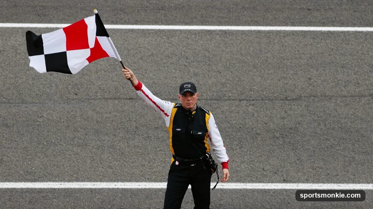 A marshal waving a red flag at the side of a Formula 1 circuit as cars slow down