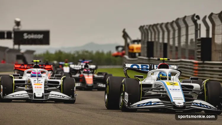 The Formula 1 safety car leading a bunched-up field of grand prix cars at reduced speed with orange lights on