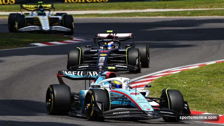 A pack of Formula 1 cars racing closely on the opening lap of a short Saturday sprint race