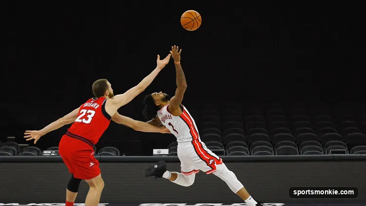 An NBA player leaping backward to release a fadeaway jump shot over a defender