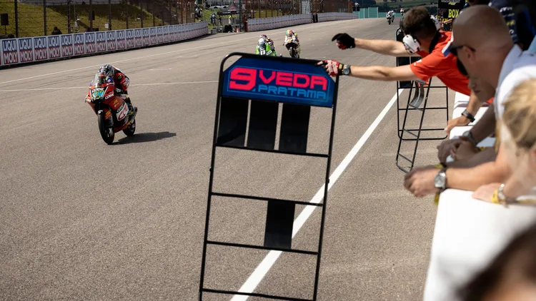 File photo from the 2026 German Grand Prix: a Moto3 race at the Sachsenring, with a pit board out for Veda Pratama, one of the riders whose results the Fernandez reinstatement can move. It does not show Adrian Fernandez. Public domain.