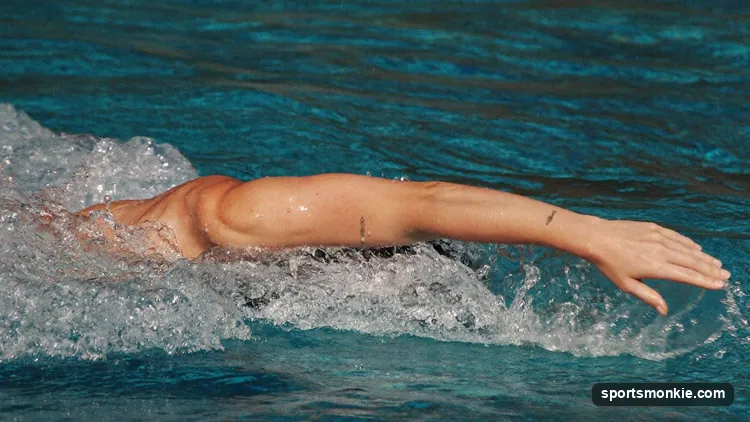 Swimmer performing freestyle front crawl stroke with arm extended and body rotated in a competition pool