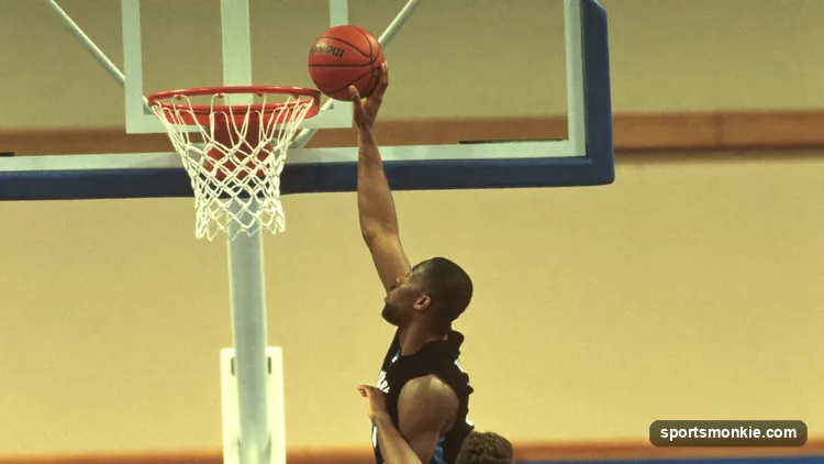 NBA post player releasing a one-handed hook shot in a high arc over a defender near the basket