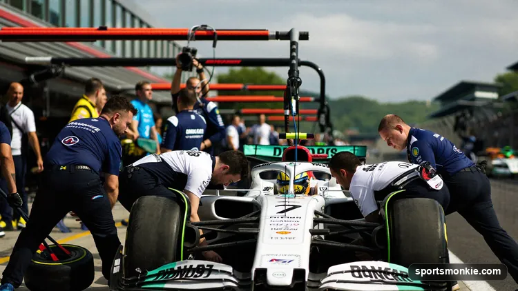 A Formula 1 pit crew of around twenty mechanics changing all four tyres on a car during a stop