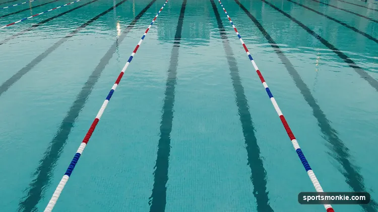 An empty competition lap pool with straight lane lines stretching to the far wall