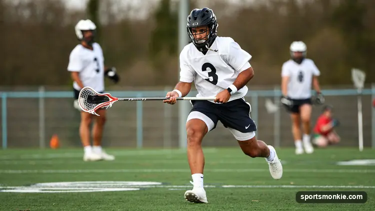 A lacrosse player reaching out with an open stick to catch a pass during a practice on a turf field