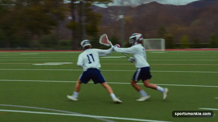 A men's lacrosse defender delivering a legal body check on an opposing ball carrier