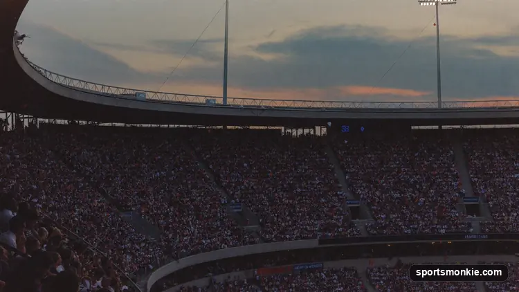 A vast packed sports stadium seen from high in the stands under floodlights