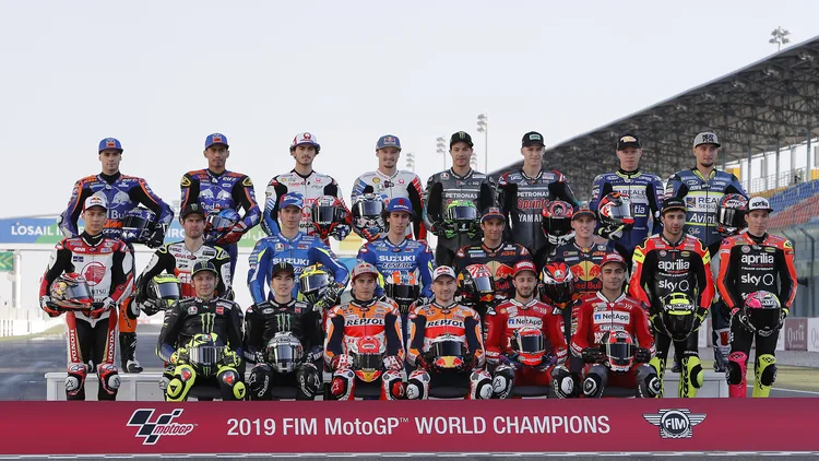 File photo from March 7, 2019: the MotoGP class of 2019 posed at the Lusail circuit in Qatar, with Marc Marquez seated in the front row in Repsol Honda colours. It is a 2019 file photo and does not show the 2026 paddock or Phillip Island. The cropped derivative is offered under the same CC BY 2.0 licence as the original.