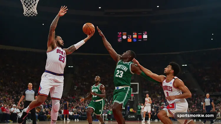 Basketball being passed across a court with an arena crowd behind