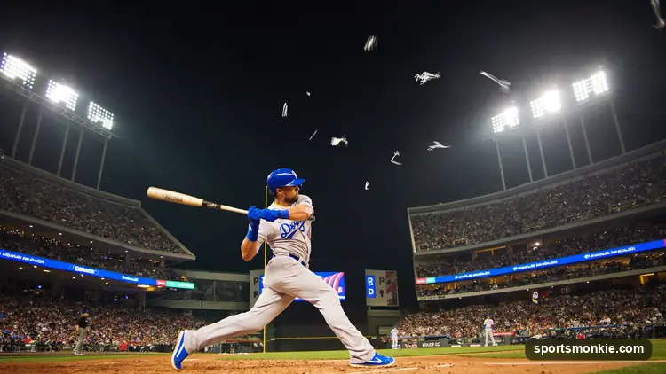 Baseball player swinging at the plate under stadium lights with the bases loaded