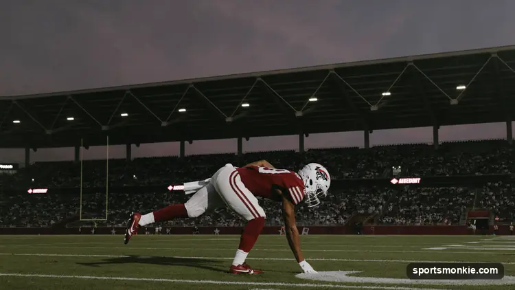 American football resting on a stadium field under bright lights