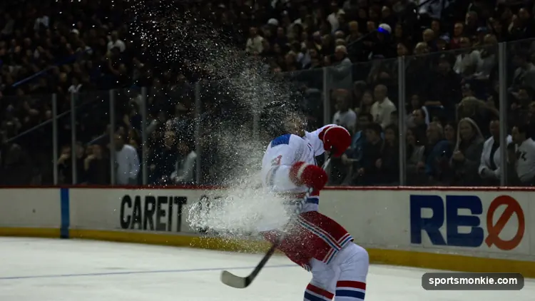 Hockey puck and stick on the ice with an arena scoreboard glowing above