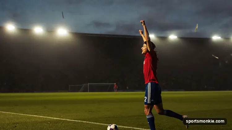 Football striker celebrating a goal in front of a packed Premier League stadium