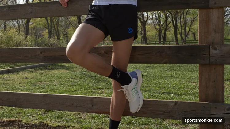 A runner performing a standing calf stretch against a wall after finishing a run