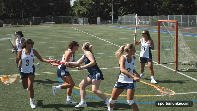 Women's lacrosse attacker driving toward goal as a defender clears the shooting lane