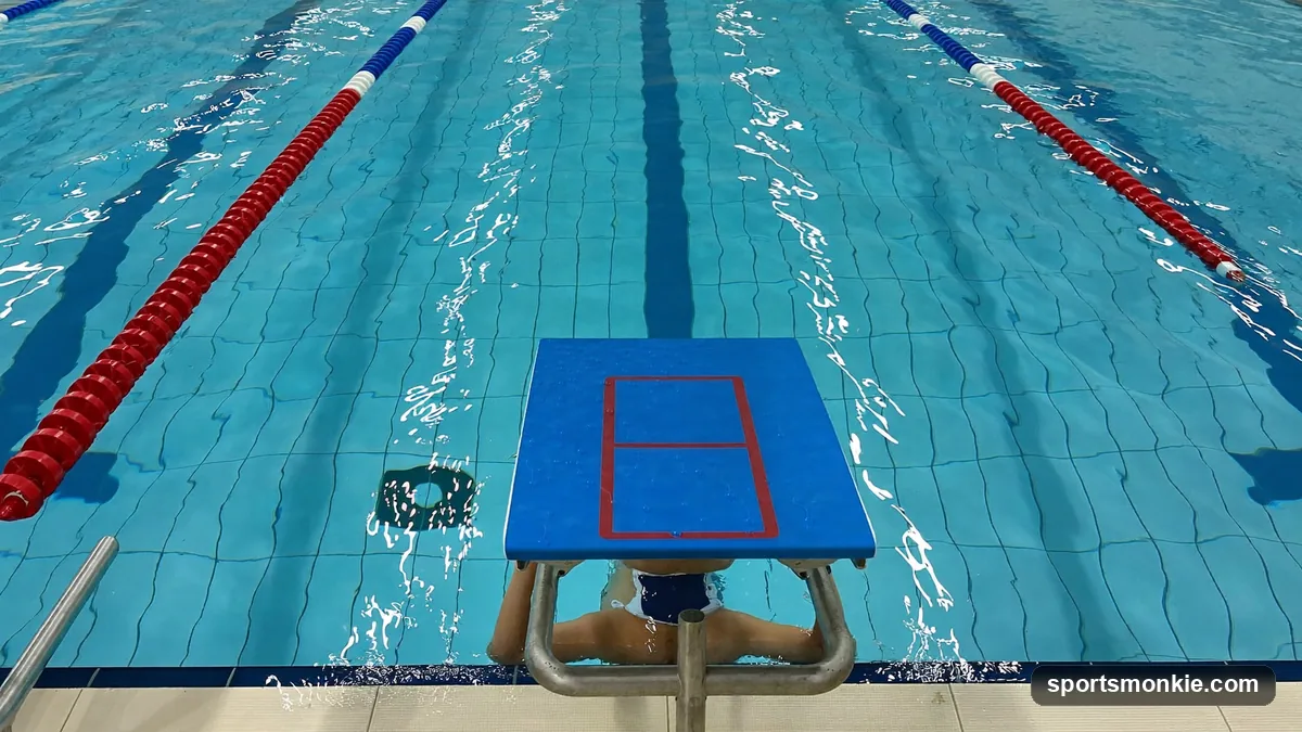 Beginner swimmer practicing a kickboard flutter-kick drill along a pool lane
