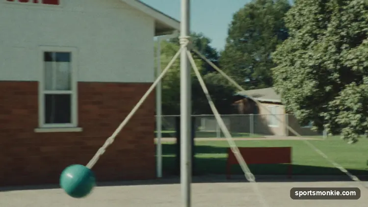 Two players on opposite sides of a tetherball pole hitting the roped ball in opposite directions