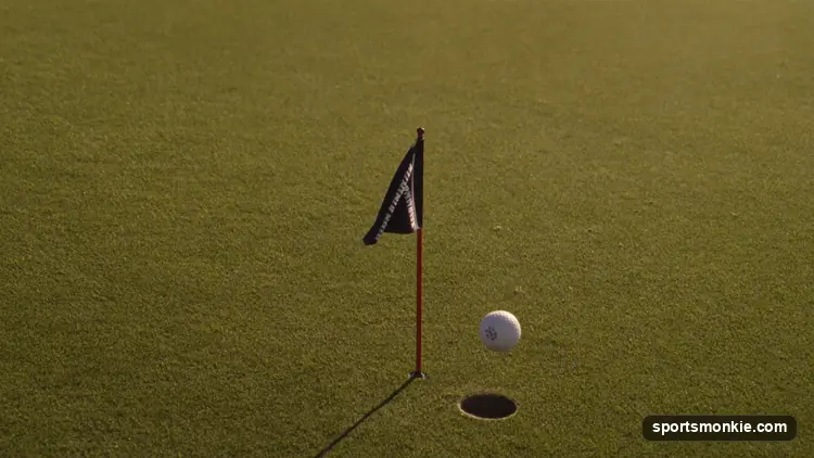 Golf ball dropping into the cup on a green with the flagstick nearby