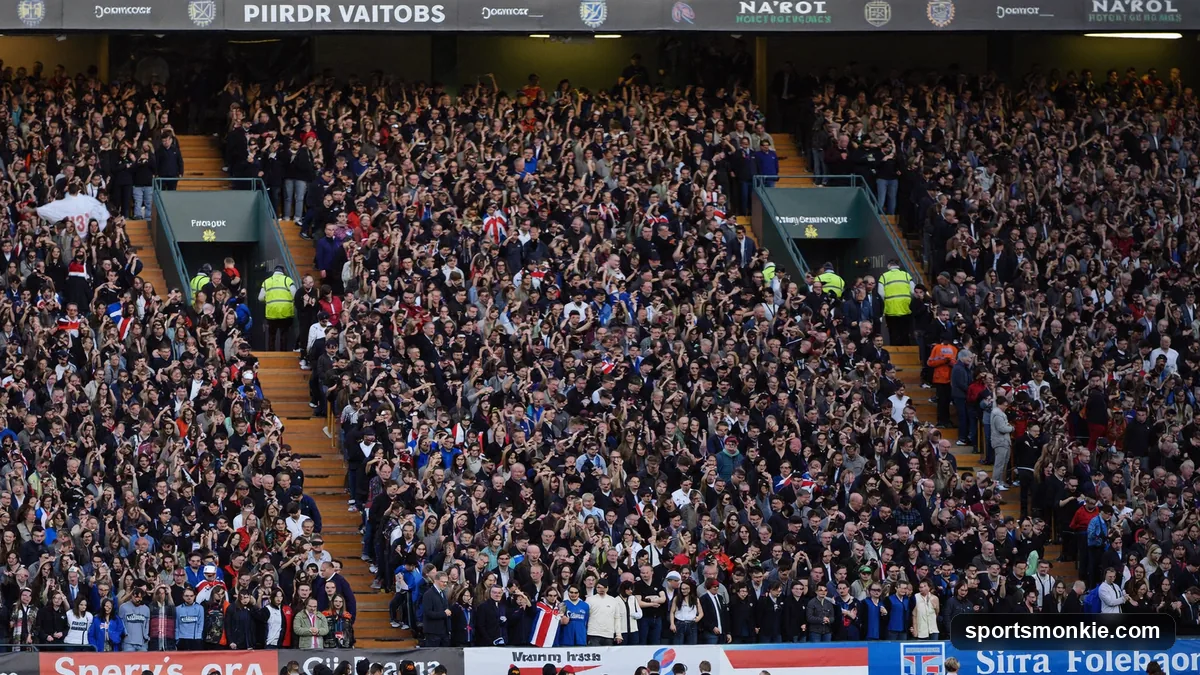 Two sets of rival football fans in contrasting colours filling a stadium on derby day