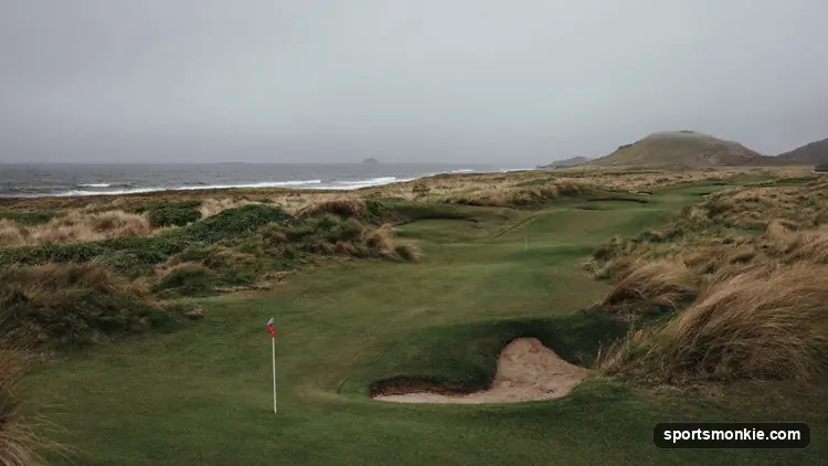 Coastal links golf course with sand dunes, fescue rough, deep pot bunkers and no trees under a windy sky