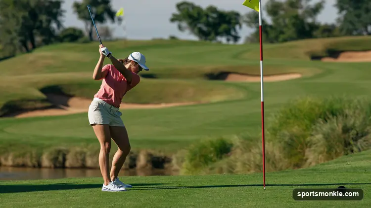 Amateur golfer hitting an iron approach shot from the fairway on a sunny day