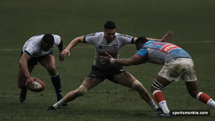 Two packs of rugby forwards bound together and pushing in a scrum as the ball is fed in