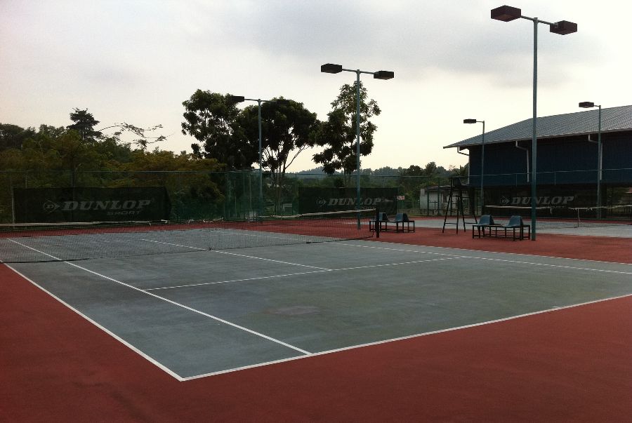 A hard surface tennis court with clay surroundings.