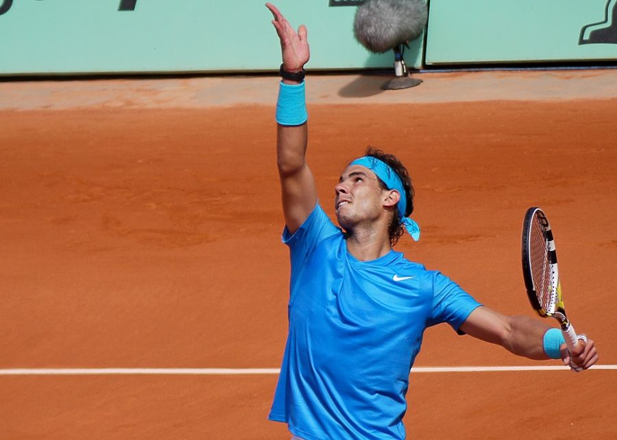 Rafael Nadal in blue uniform executing his serve